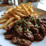 A Korean-style ground beef dish featuring tender and flavorful ground beef covered in a glaze, served with French fries.