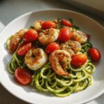Zucchini noodle pesto with cherry tomatoes and grilled shrimp .